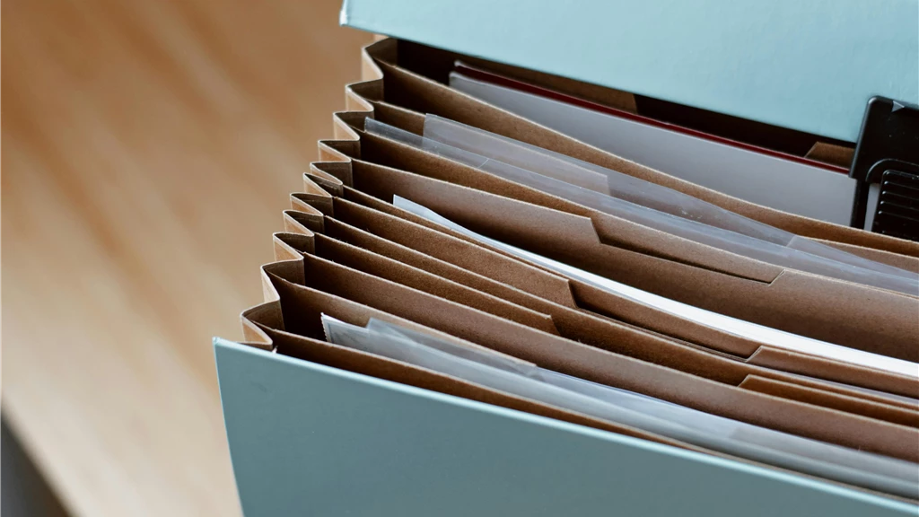 From above of opened modern briefcase with prepared papers placed on timber table in soft focus