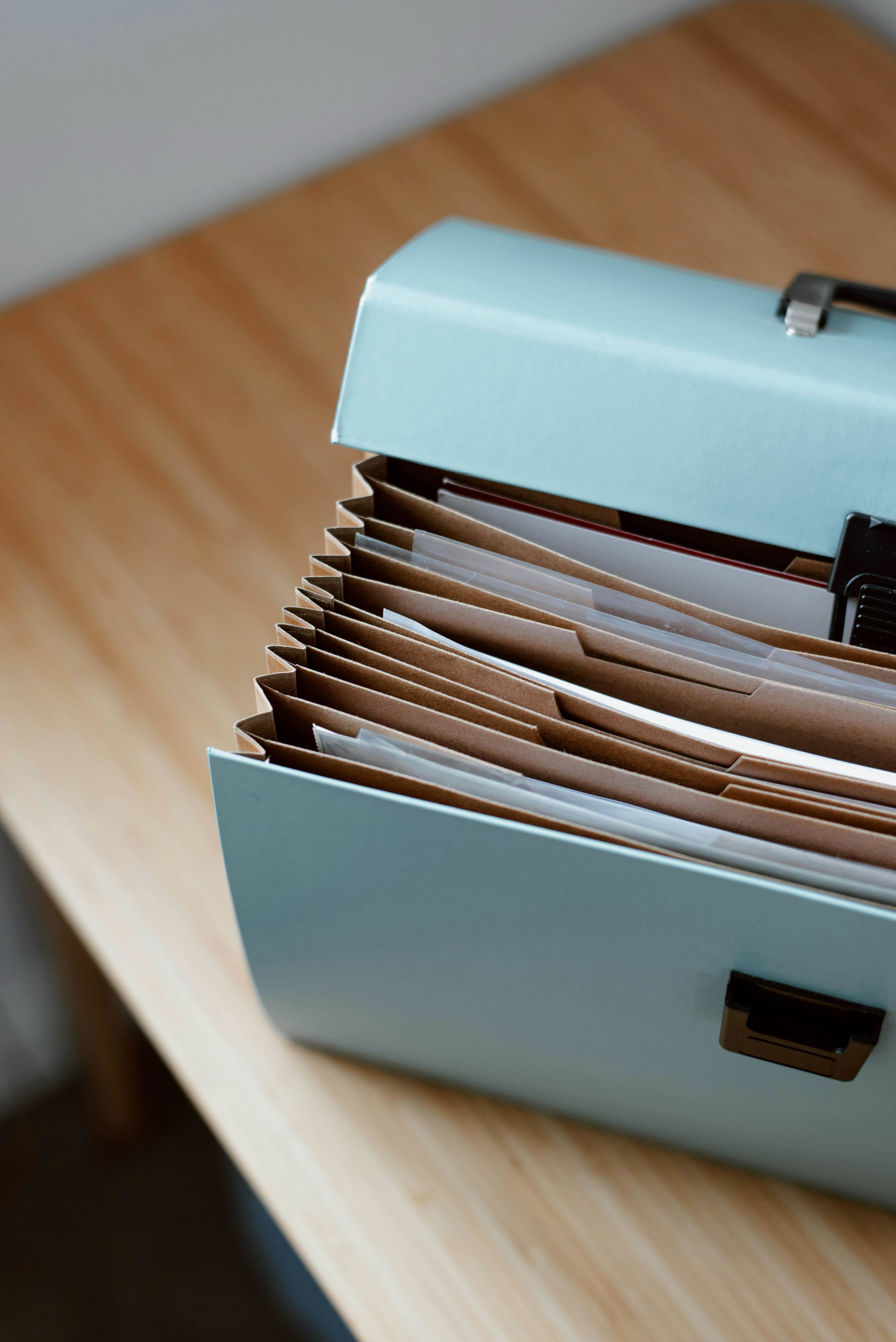 From above of opened modern briefcase with prepared papers placed on timber table in soft focus